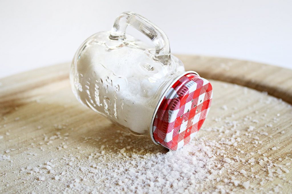 Use your fingers to sprinkle salt from an open can of salt